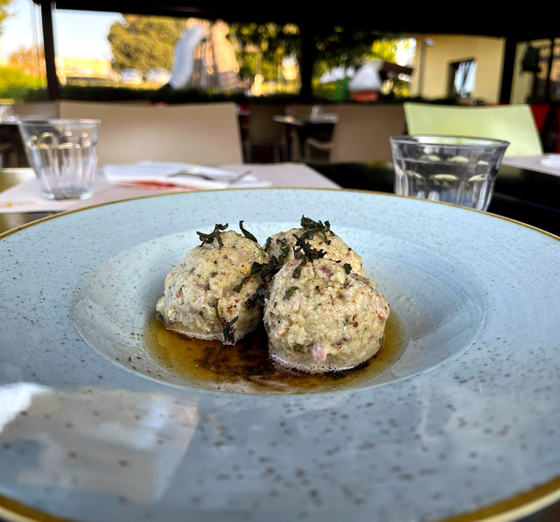 Piatto di canederli con speck, fonduta al Branzi ed erba cipollina, specialità bavarese